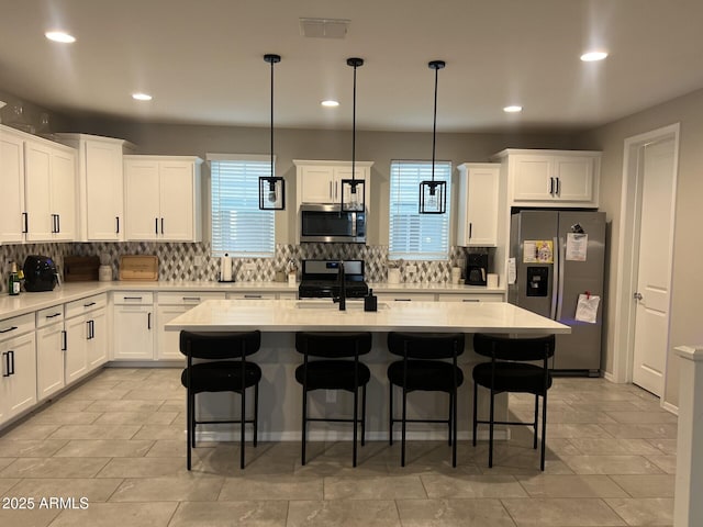613 W Winchester Dr, Chandler, AZ 85286 - kitchen with appliances with stainless steel finishes, a sink, decorative backsplash, white cabinetry, and a breakfast bar