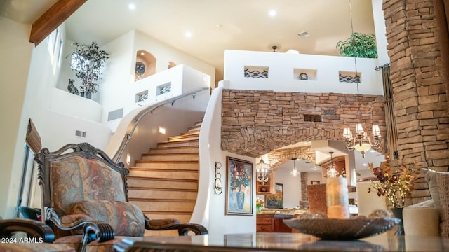 staircase featuring a notable chandelier, beam ceiling, and a high ceiling