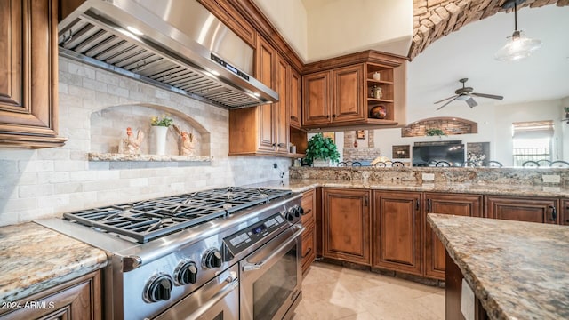 kitchen featuring decorative backsplash, ceiling fan, wall chimney range hood, decorative light fixtures, and high end stainless steel range