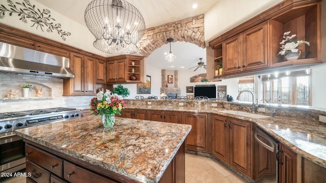 kitchen featuring sink, decorative backsplash, light stone countertops, appliances with stainless steel finishes, and extractor fan