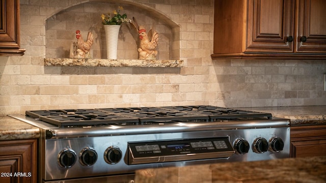 kitchen featuring light stone countertops, range, and tasteful backsplash