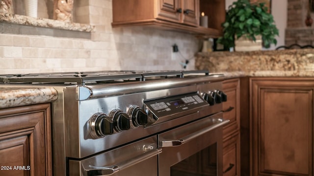 room details with tasteful backsplash, light stone counters, and high end stove