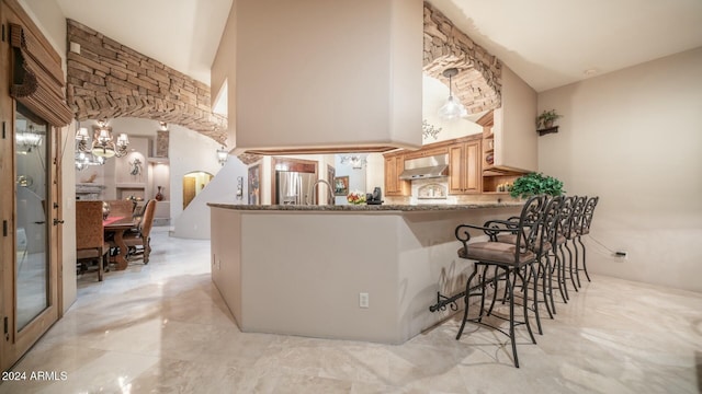 kitchen featuring kitchen peninsula, stainless steel refrigerator with ice dispenser, exhaust hood, high vaulted ceiling, and a breakfast bar area