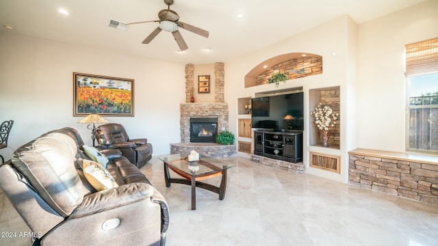 living room with built in shelves, ceiling fan, and a stone fireplace