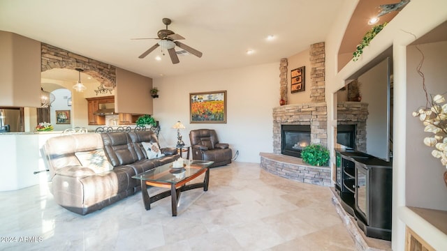 living room with a stone fireplace and ceiling fan