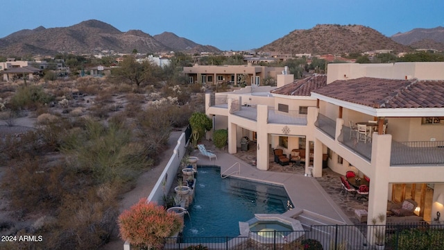 exterior space with a mountain view, a swimming pool with hot tub, a balcony, and a patio area