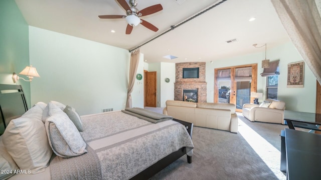 carpeted bedroom featuring ceiling fan and a fireplace