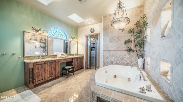 bathroom featuring a skylight, tile walls, vanity, and tiled tub