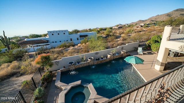 view of swimming pool with a patio area, a mountain view, and an in ground hot tub