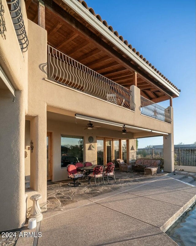 rear view of house featuring ceiling fan, a balcony, and a patio