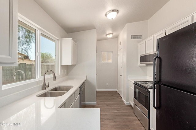 2318 N 87th Ave, Phoenix, AZ 85037 - kitchen featuring appliances with stainless steel finishes, white cabinetry, light countertops, and wood finished floors