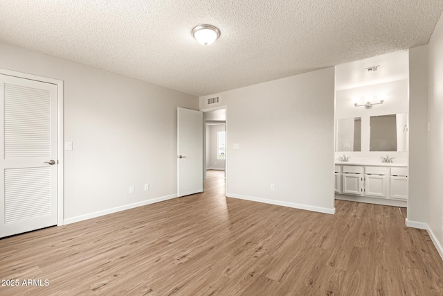 2318 N 87th Ave, Phoenix, AZ 85037 - unfurnished bedroom featuring light wood-style flooring, a textured ceiling, and ensuite bathroom