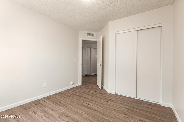 2318 N 87th Ave, Phoenix, AZ 85037 - unfurnished bedroom featuring wood finished floors, a textured ceiling, and a closet