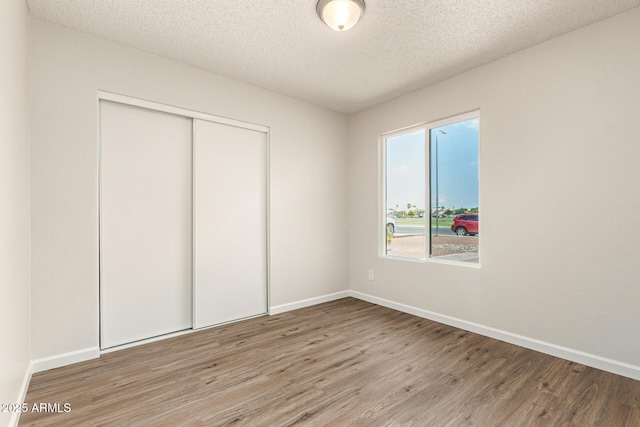 2318 N 87th Ave, Phoenix, AZ 85037 - unfurnished bedroom with wood finished floors, a closet, and a textured ceiling