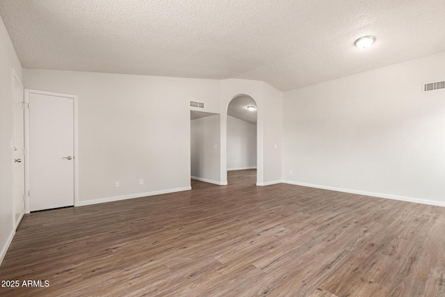 2318 N 87th Ave, Phoenix, AZ 85037 - spare room with a textured ceiling, wood finished floors, vaulted ceiling, and arched walkways