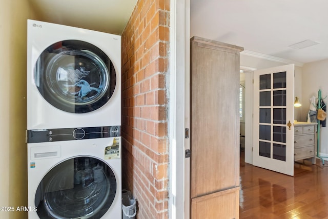 washroom with stacked washing maching and dryer and wood-type flooring