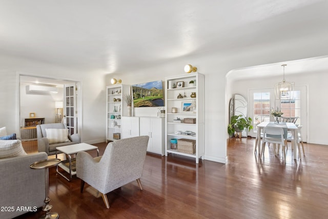 living room featuring an AC wall unit, a notable chandelier, and dark hardwood / wood-style flooring