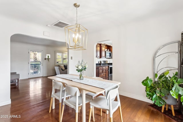 dining space featuring dark hardwood / wood-style flooring and an inviting chandelier