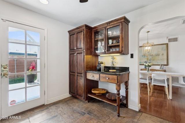 bar featuring pendant lighting, dark brown cabinets, and a chandelier