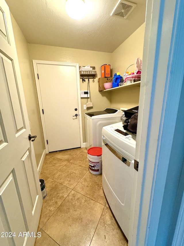 washroom with light tile patterned floors, washing machine and dryer, and a textured ceiling