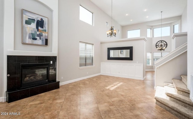 living room featuring a towering ceiling, a notable chandelier, and a fireplace