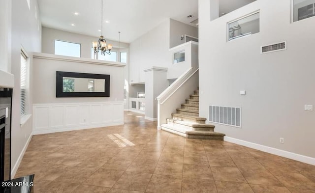 tiled entrance foyer featuring an inviting chandelier and a towering ceiling