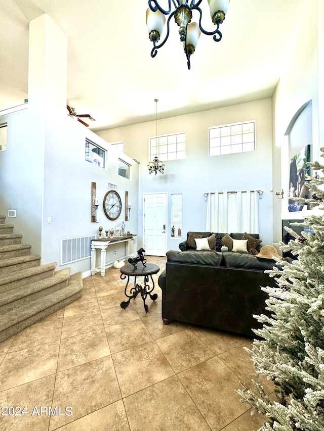 living room with a towering ceiling, ceiling fan with notable chandelier, and tile patterned floors