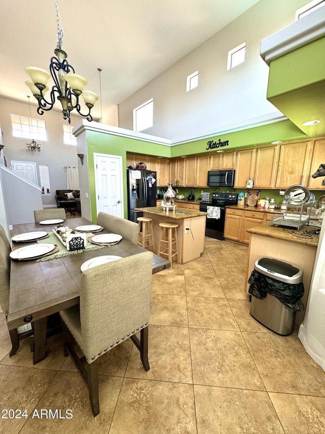 kitchen with black appliances, light tile patterned floors, a notable chandelier, pendant lighting, and a high ceiling