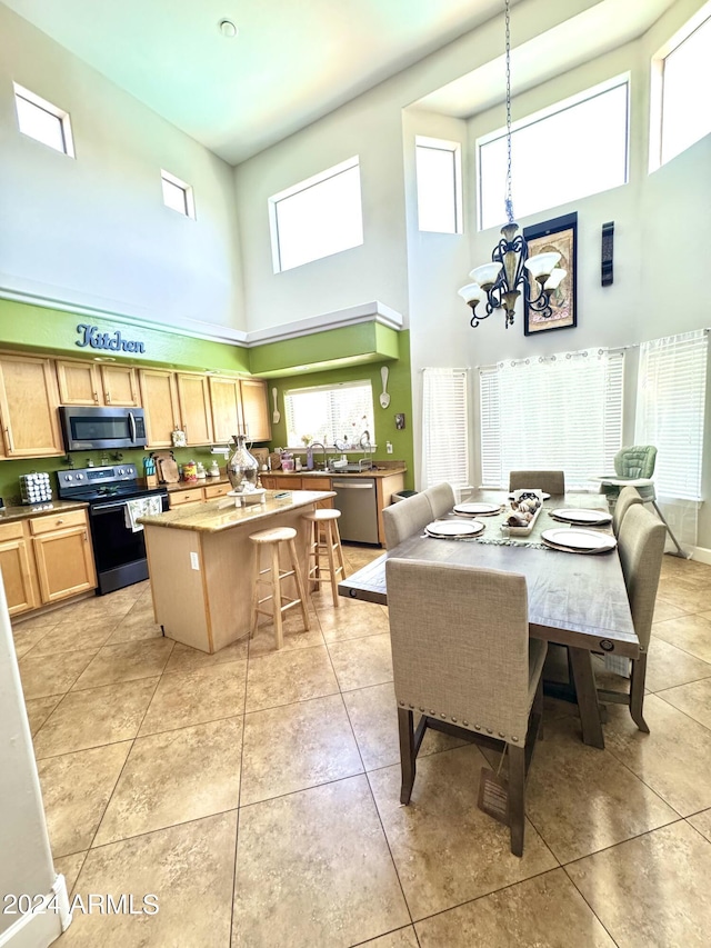 tiled dining room with a healthy amount of sunlight, a chandelier, and a high ceiling