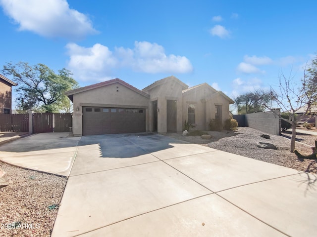 view of front of house with stucco siding, an attached garage, concrete driveway, and fence