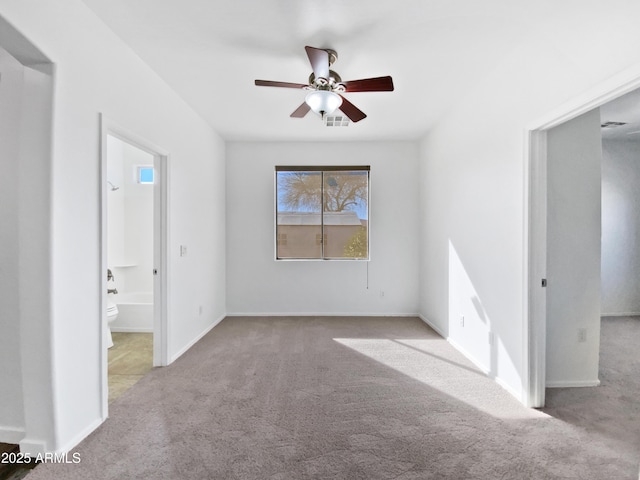 spare room with baseboards, carpet floors, visible vents, and a ceiling fan