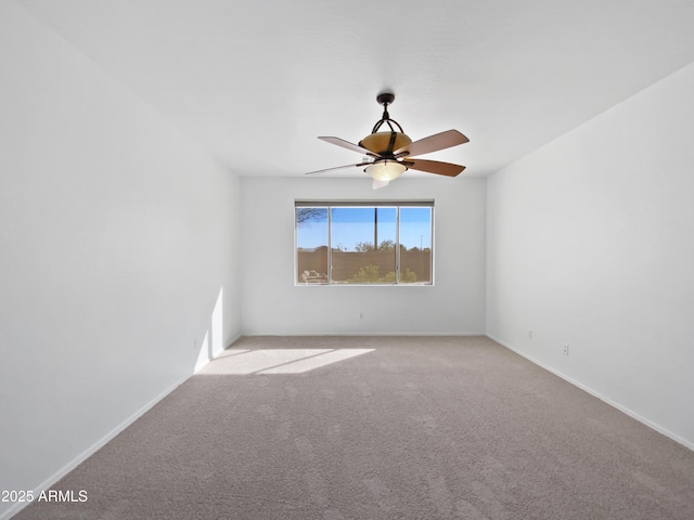 carpeted empty room featuring baseboards and a ceiling fan