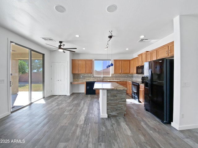 kitchen with visible vents, backsplash, a center island, wood finished floors, and black appliances