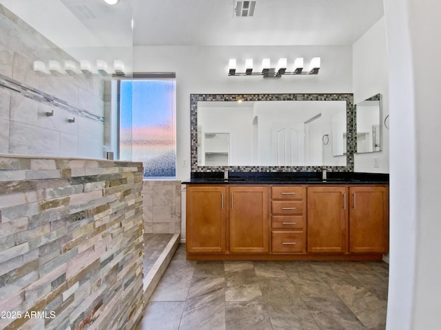 full bath featuring double vanity, a walk in shower, visible vents, and a sink