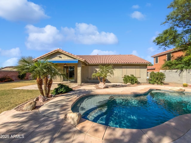 rear view of property with stucco siding, a tile roof, fence, a fenced in pool, and a patio area