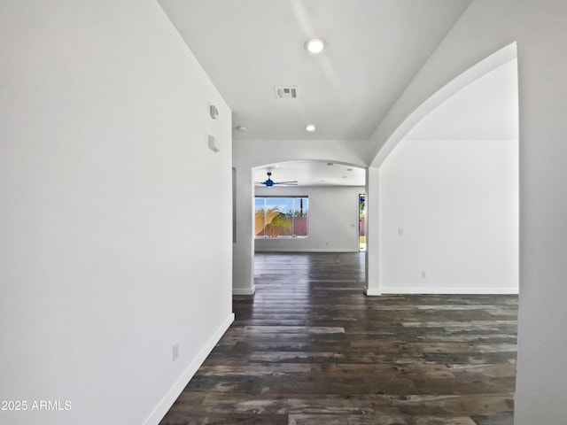 hallway with wood finished floors, visible vents, baseboards, recessed lighting, and arched walkways