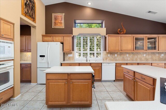 kitchen featuring decorative backsplash, white appliances, vaulted ceiling, and a kitchen island