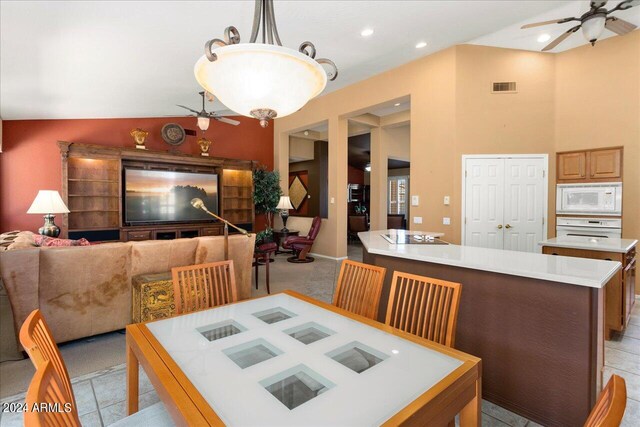 dining space with ceiling fan, light tile patterned floors, and vaulted ceiling