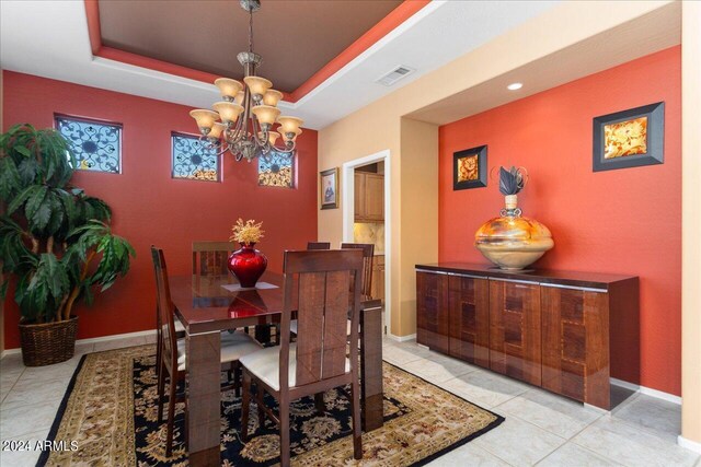 tiled dining area featuring an inviting chandelier and a raised ceiling