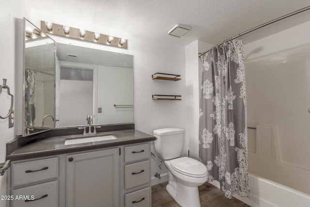 full bathroom with toilet, hardwood / wood-style flooring, shower / bath combo, a textured ceiling, and vanity