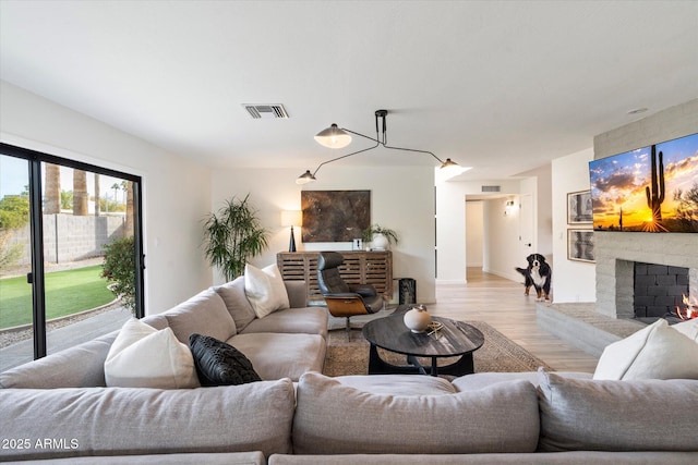 living room featuring light wood-type flooring and a brick fireplace