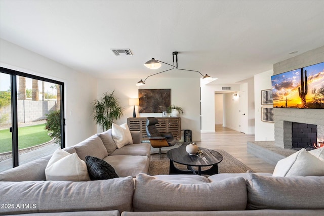 living room with light hardwood / wood-style floors and a stone fireplace