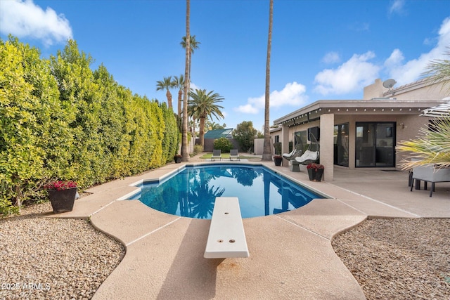 view of swimming pool featuring a diving board and a patio