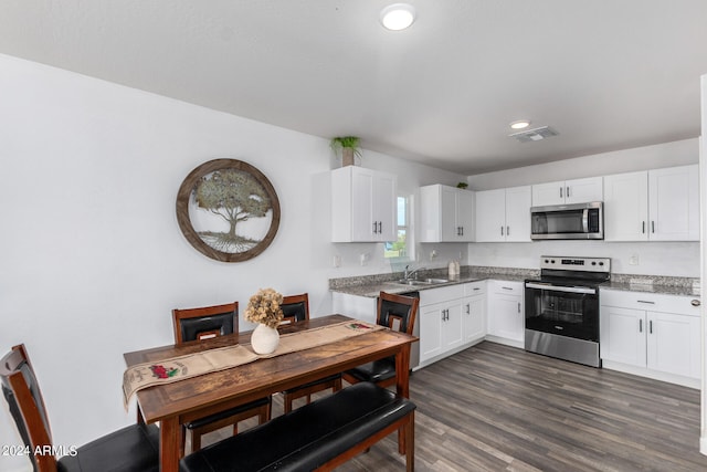 kitchen featuring appliances with stainless steel finishes, dark wood-type flooring, sink, light stone counters, and white cabinets