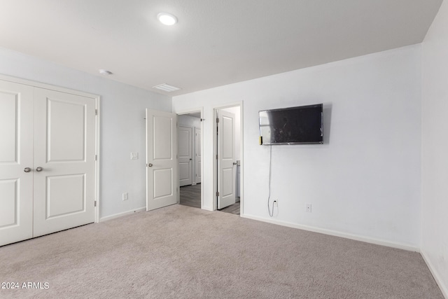 unfurnished bedroom featuring a closet and light carpet