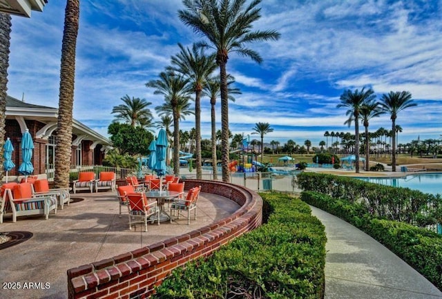 view of property's community featuring playground community, a swimming pool, and a patio