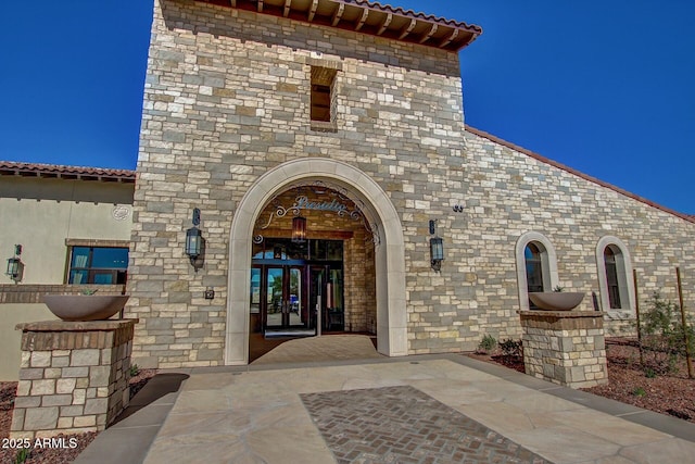 property entrance with french doors, stone siding, and stucco siding