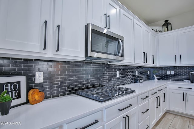 kitchen with white cabinets, appliances with stainless steel finishes, and backsplash