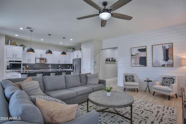 living room featuring ceiling fan, light hardwood / wood-style flooring, and sink