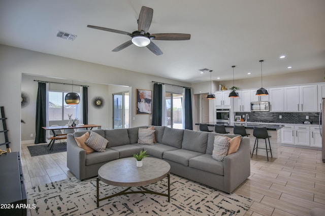 living room featuring light hardwood / wood-style flooring, plenty of natural light, and ceiling fan